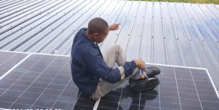 A Pawafactory technician working on solar panels laid across a sloped metal roof